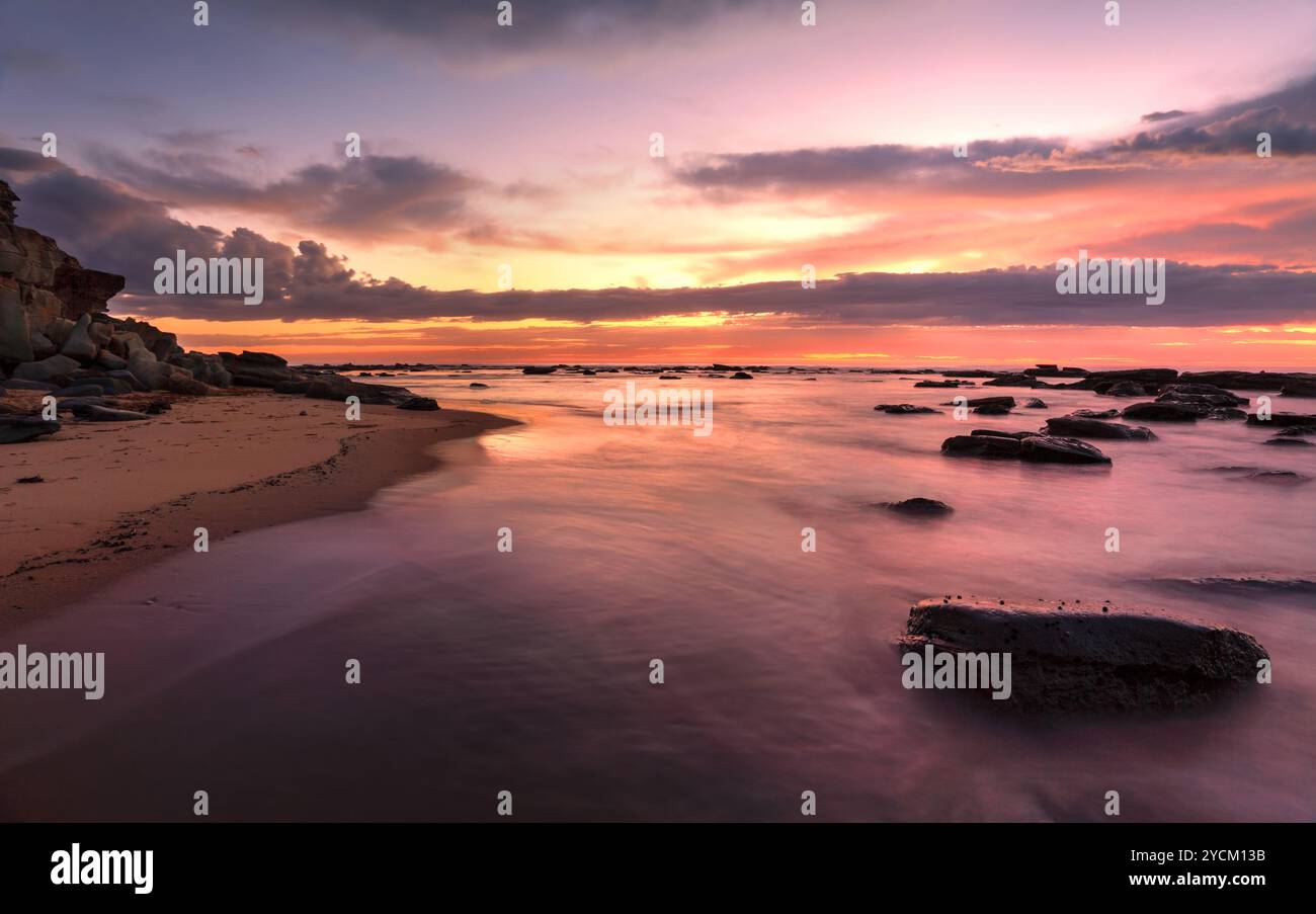 Magnifica sunrise alta marea a Bateau Bay rockshelf Foto Stock