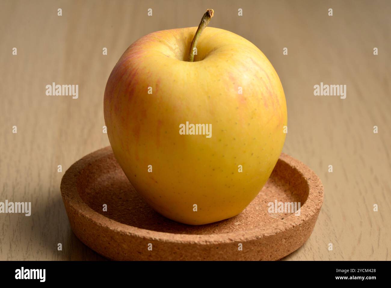 Una mela singola su un vassoio centrale in sughero Foto Stock