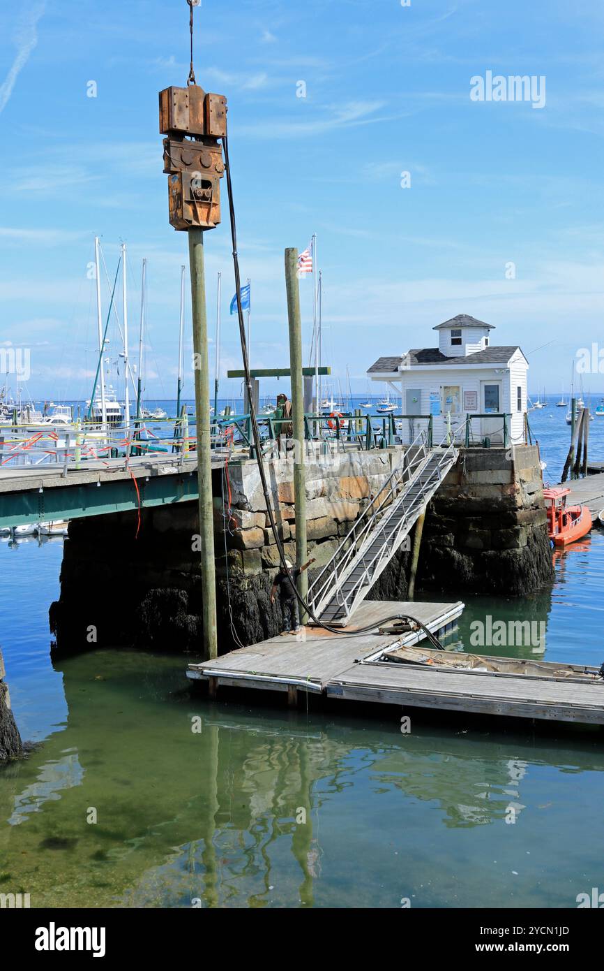 Operaio edile che supervisiona l'installazione di nuovi pali di legno per il molo presso lo sbarco pubblico nel porto di Rockland, Maine Foto Stock