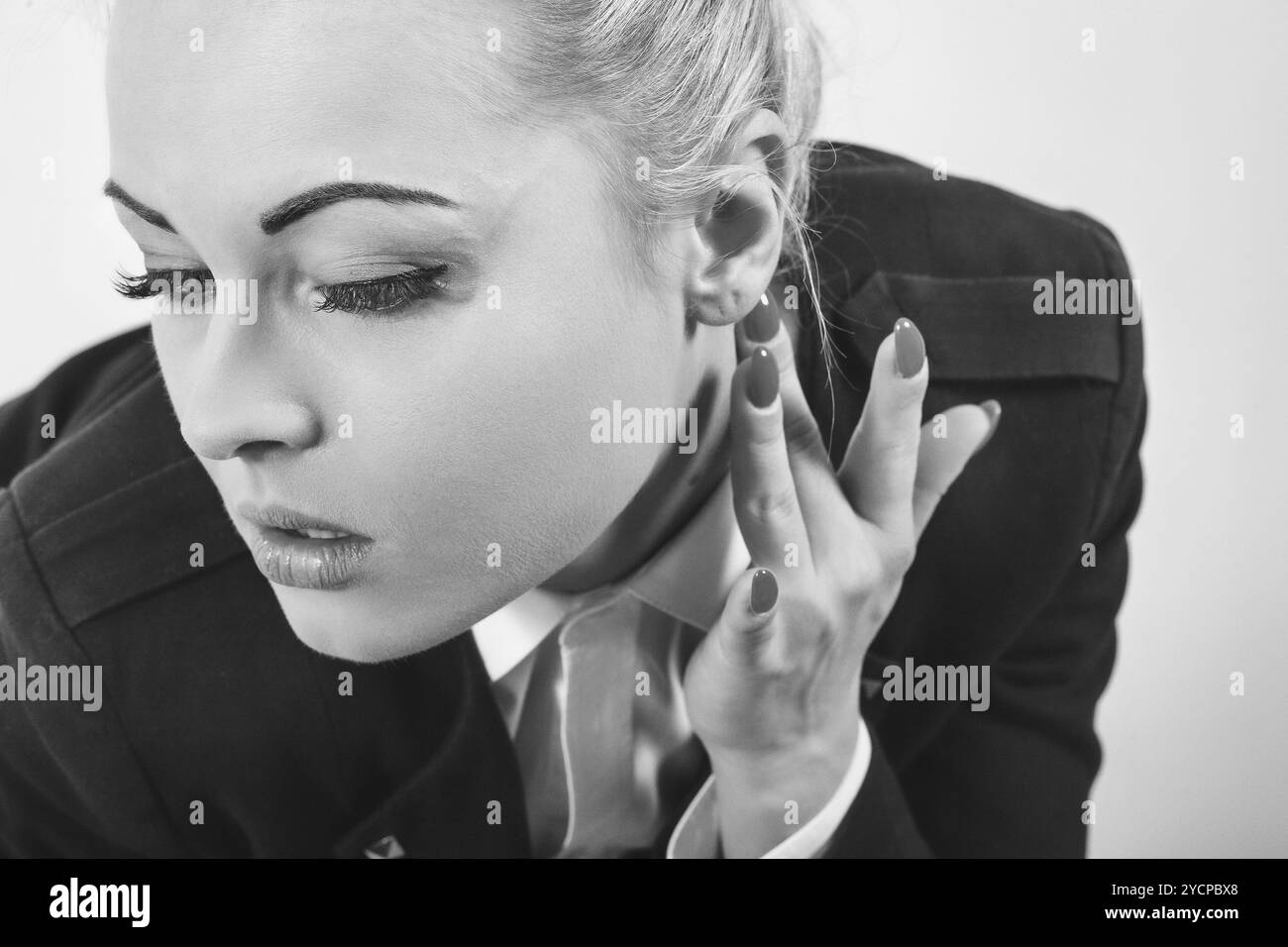 Donna d'affari sicura con smalto per unghie rosso ascolta attentamente in un ambiente da ufficio in bianco e nero. Elegante, mirata e professionale Foto Stock