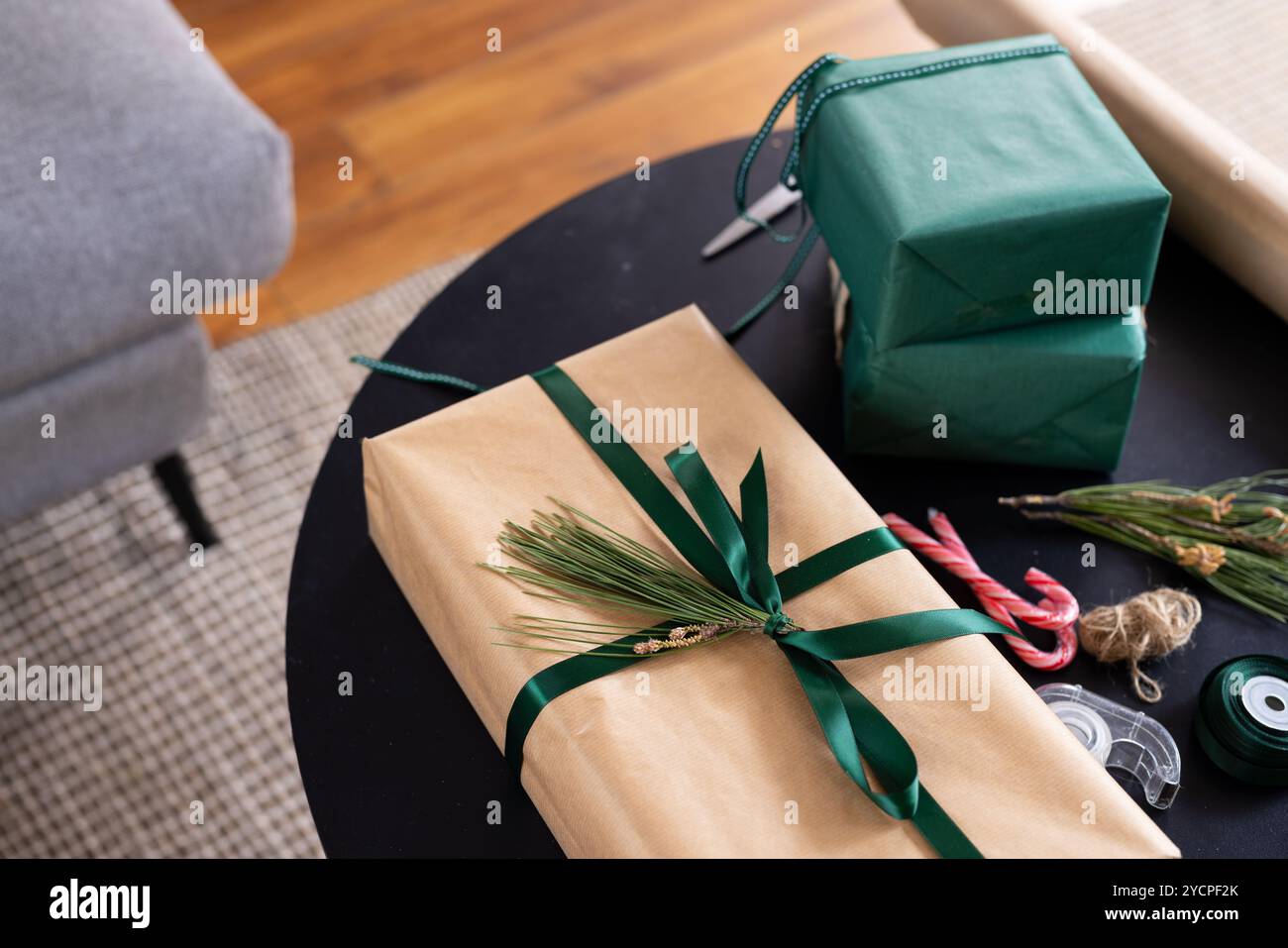 Avvolgere i regali di Natale con un nastro verde e decorazioni in pino a casa Foto Stock