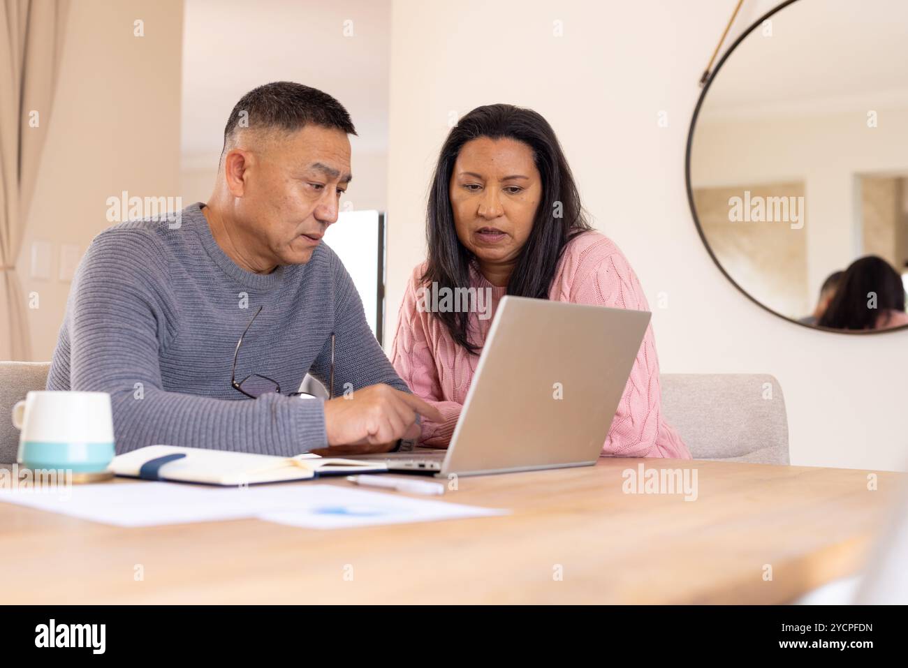 Coppia senior multirazziale che utilizza un notebook a casa, concentrandosi sullo shopping online durante le vacanze Foto Stock