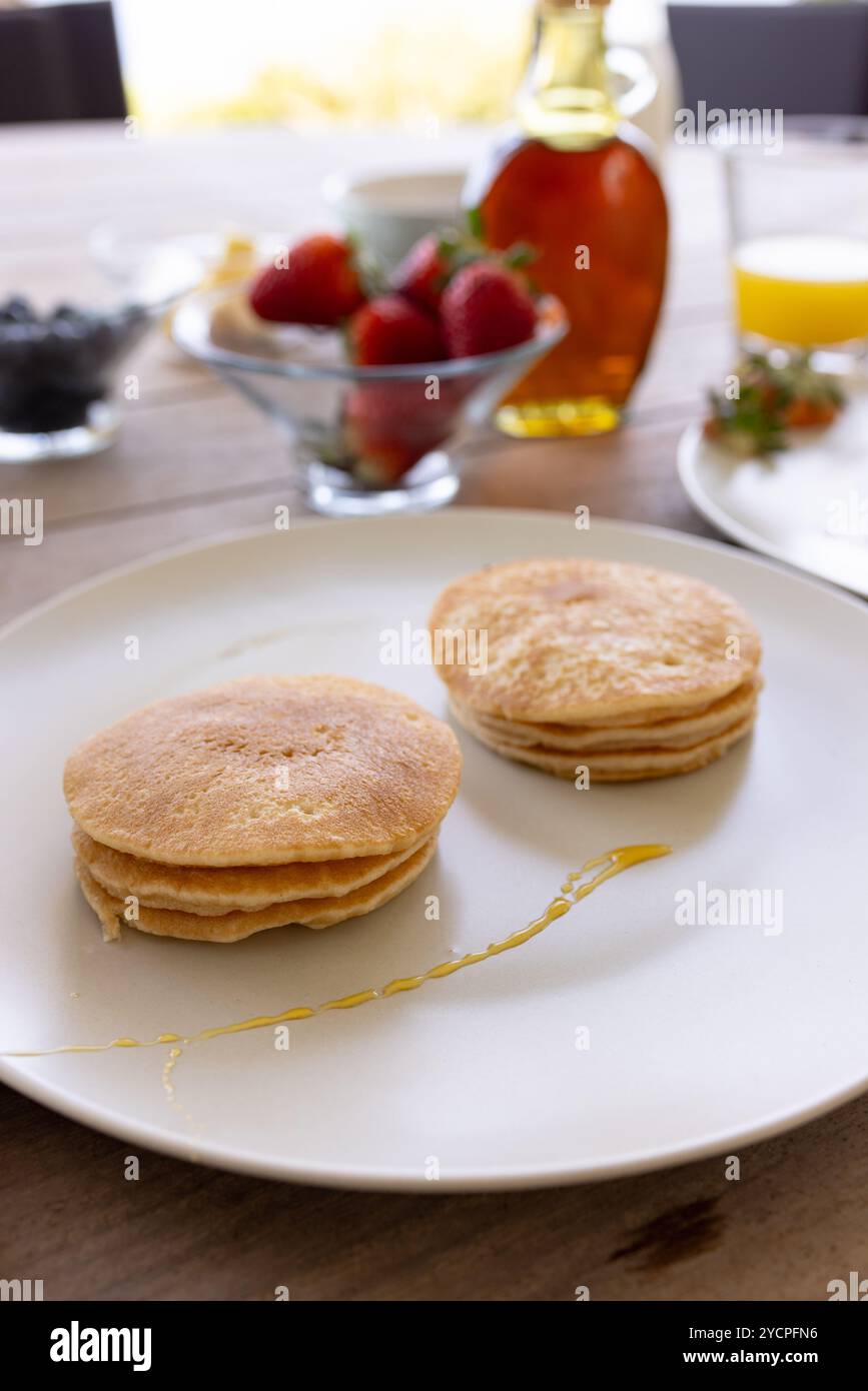 Pancake con sciroppo e frutta fresca sul tavolo della colazione, pronti da gustare, a casa Foto Stock