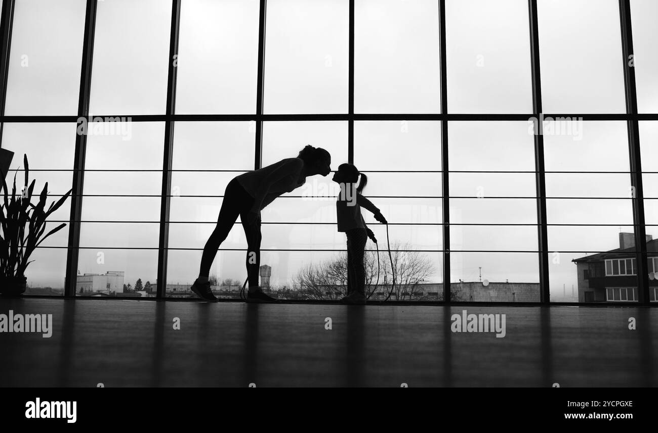 Silhouette di madre e figlia in palestra Foto Stock
