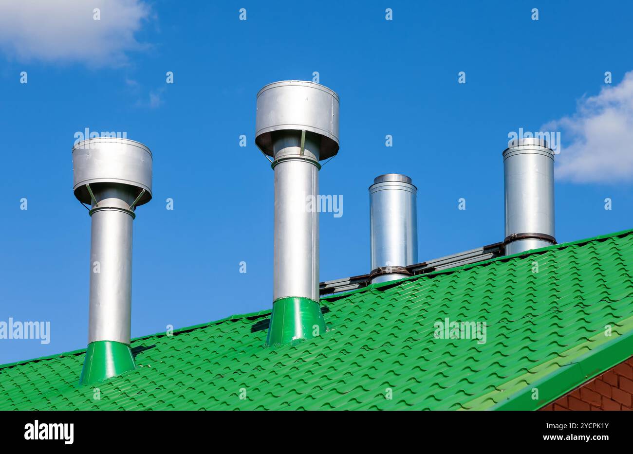Tubi di metallo su un tetto verde contro il cielo blu Foto Stock
