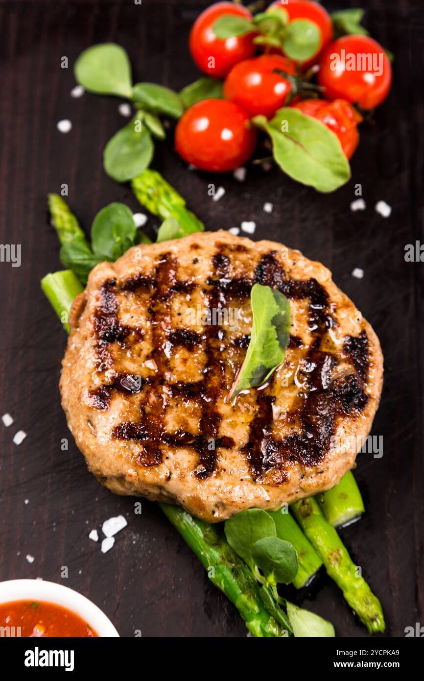 Cotoletta di carne grigliata con asparagi e pomodori Foto Stock