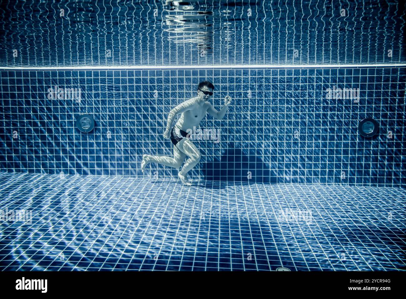 L'uomo sotto l'acqua scorre lungo il fondo di una piscina Foto Stock