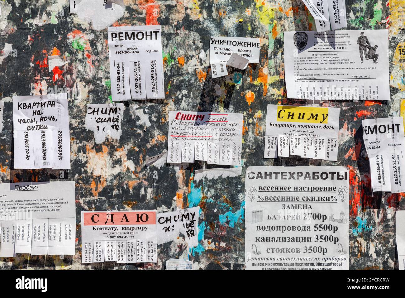 Sporco bulletin board riempito con carta avvisi su lingua russa Foto Stock