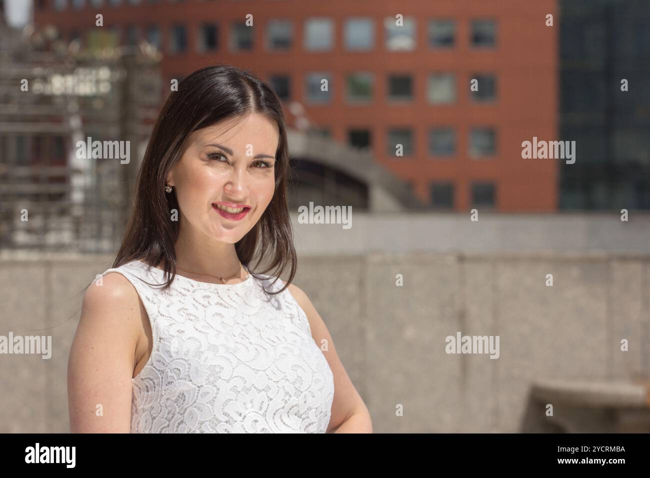 Donna felice che posa sullo sfondo urbano Foto Stock