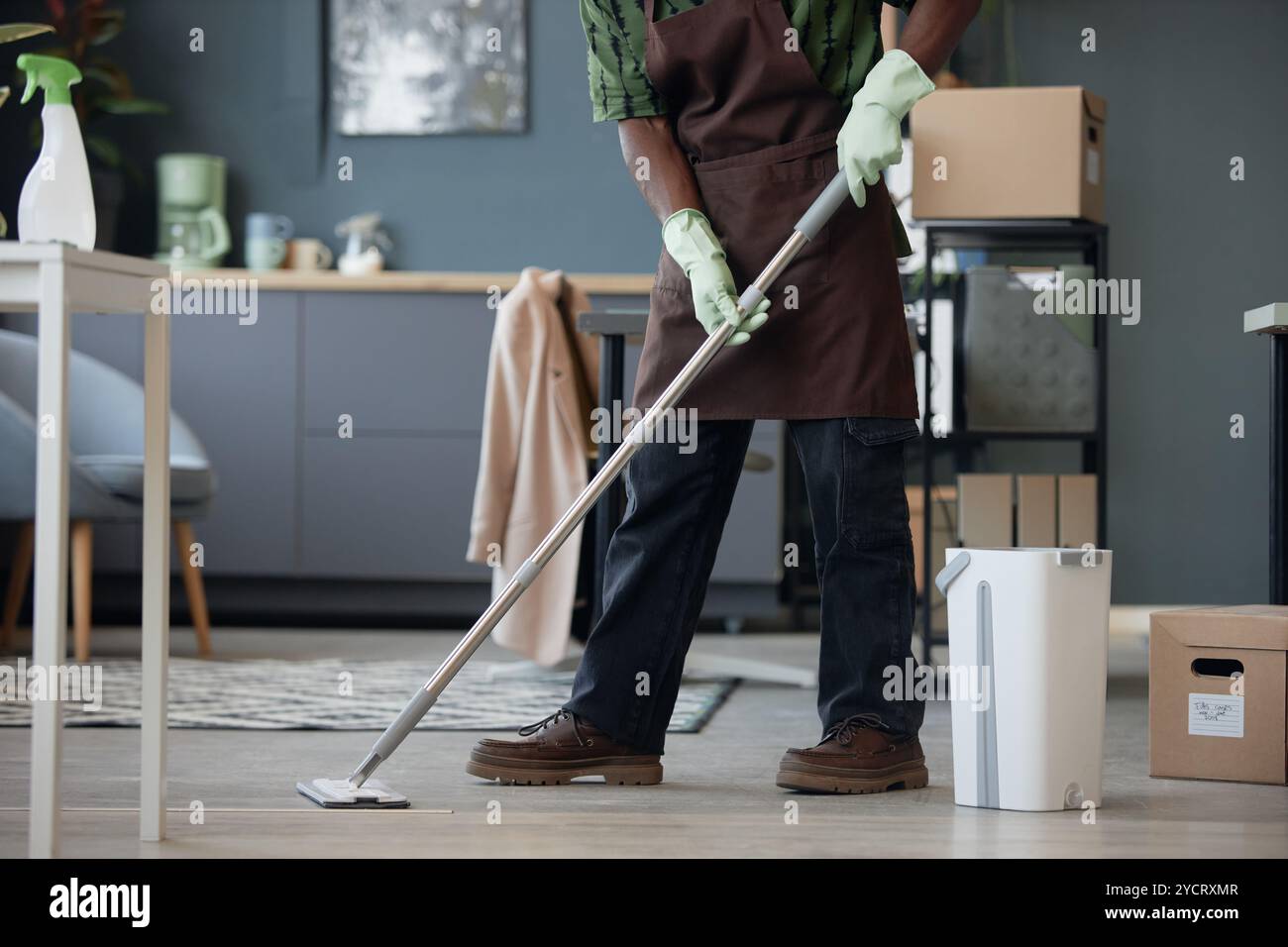 Immagine laterale ritagliata dell'irriconoscibile uomo afro-americano che pulisce l'ufficio e lava i pavimenti con mocio e secchio, spazio fotocopie Foto Stock