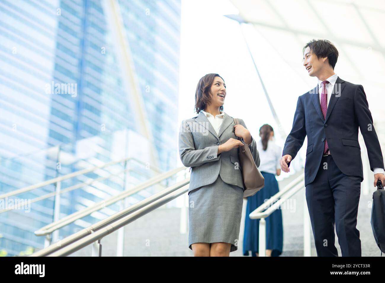 Uomo e donna in costume che chiacchierano e ridevano mentre camminavano lungo una strada dell'ufficio Foto Stock