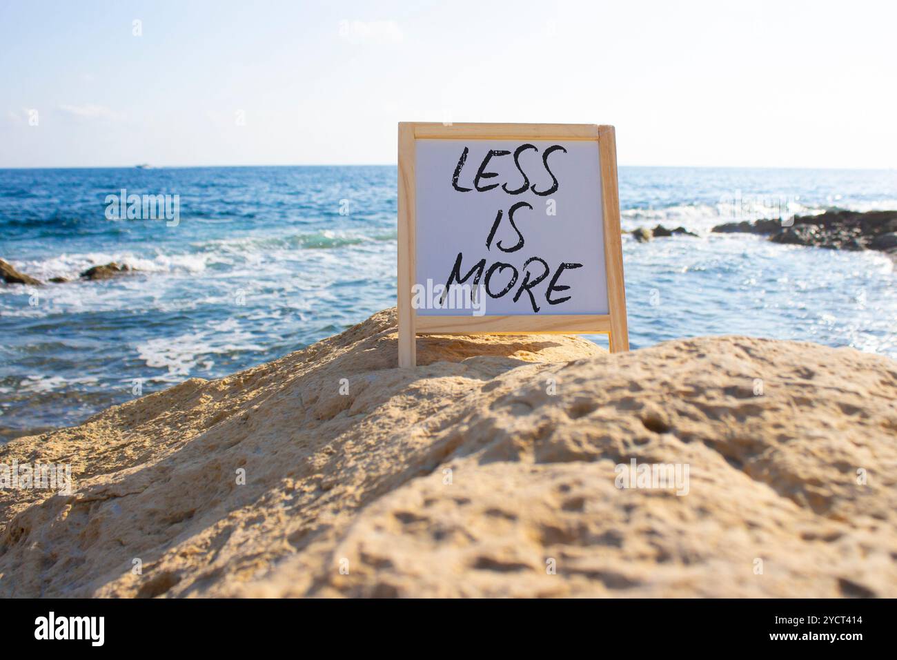 Meno è più simbolo. Lavagna bianca con parole concettuali meno è di più. Bellissimo sfondo marino. Business and Less è più concetto. Copia spazio. Foto Stock