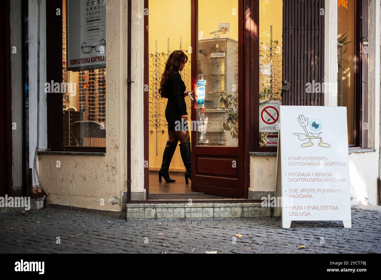 Una donna in un negozio di ottica che seleziona occhiali neri Foto Stock