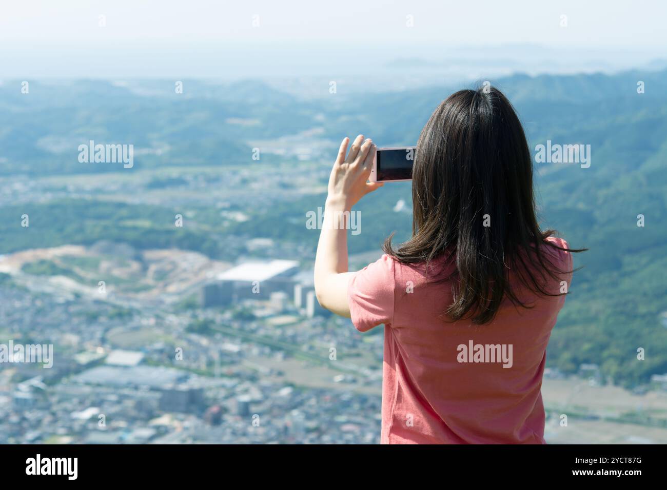 Vista posteriore di una donna che scatta una foto con uno smartphone Foto Stock