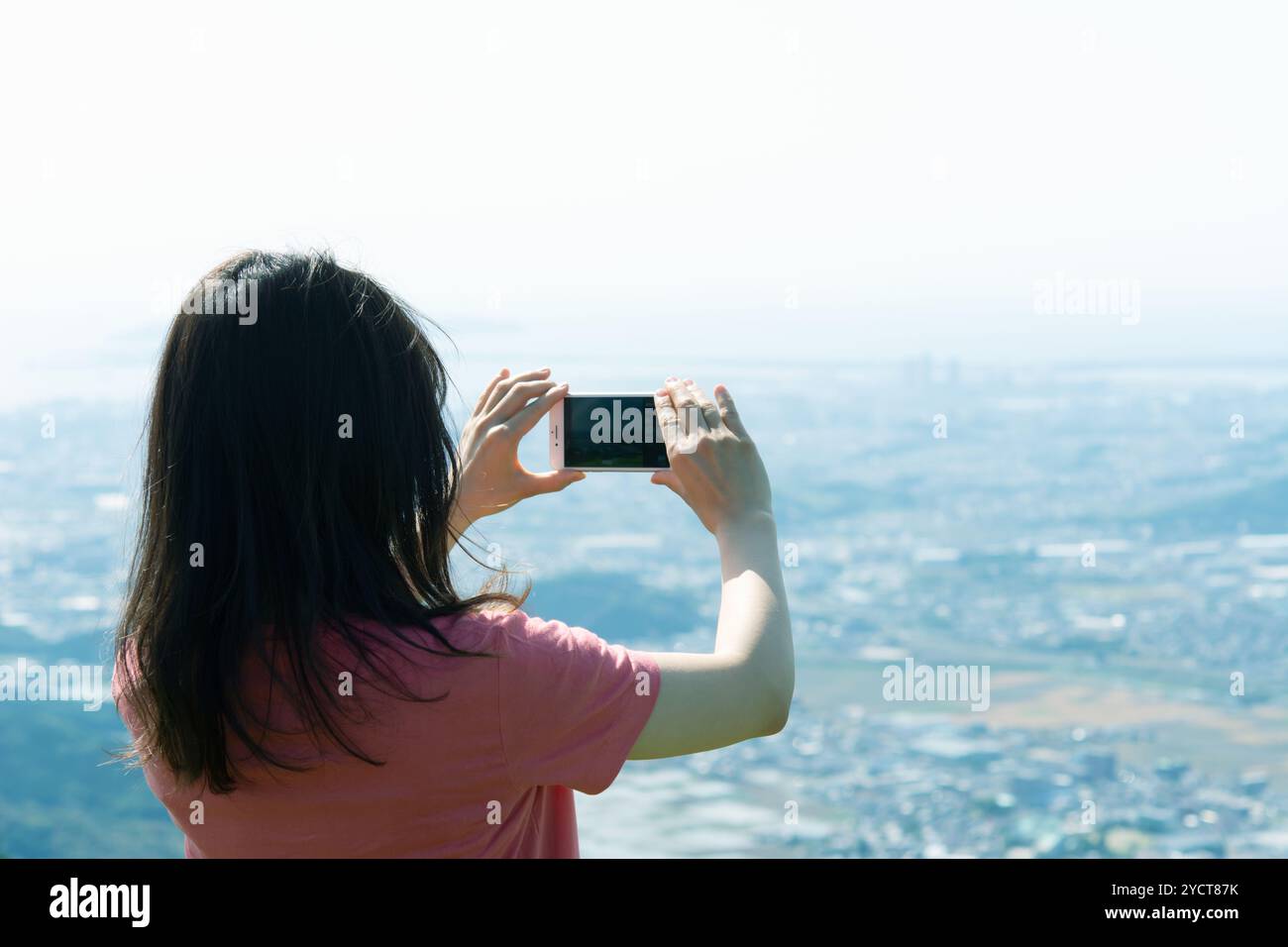 Vista posteriore di una donna che scatta una foto con uno smartphone Foto Stock