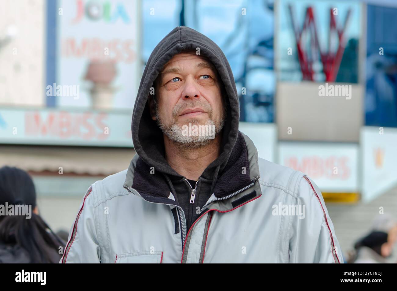 ritratto di un uomo pensivo di 50-55 anni in felpa su sfondo urbano sfocato. Foto Stock