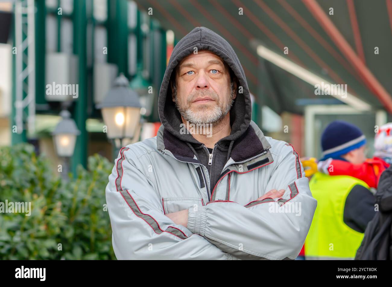 Ritratto di strada di un uomo serio di 50-55 anni con una felpa su uno sfondo urbano sfocato. Foto Stock