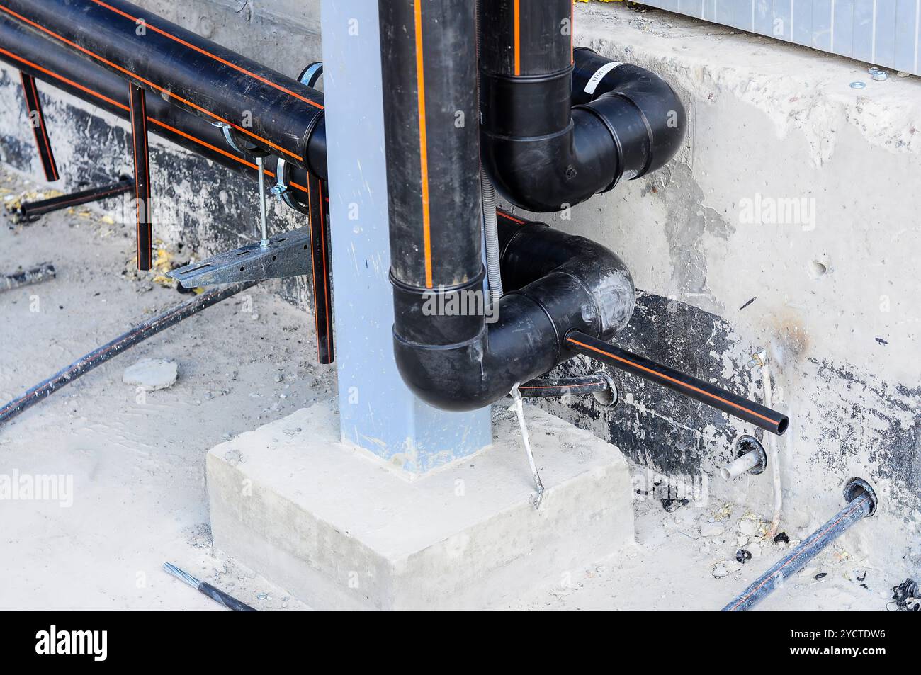 Primo piano di tubi in plastica nera installati su fondamenta in calcestruzzo, parte di un sistema di costruzione. Foto Stock