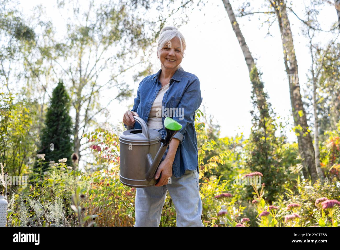Donna anziana che lavora nel suo giardino in una giornata di sole Foto Stock
