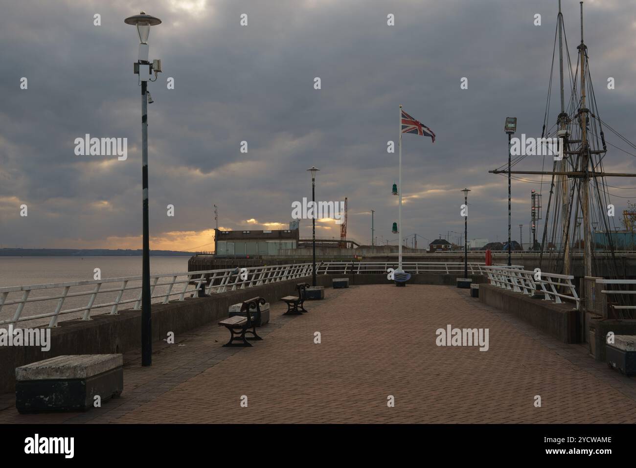 La Union Jack vola sul lato ovest di Princes Dock, al tramonto. Albert Dock in lontananza. Navi a vela ormeggiate a destra. Foto Stock
