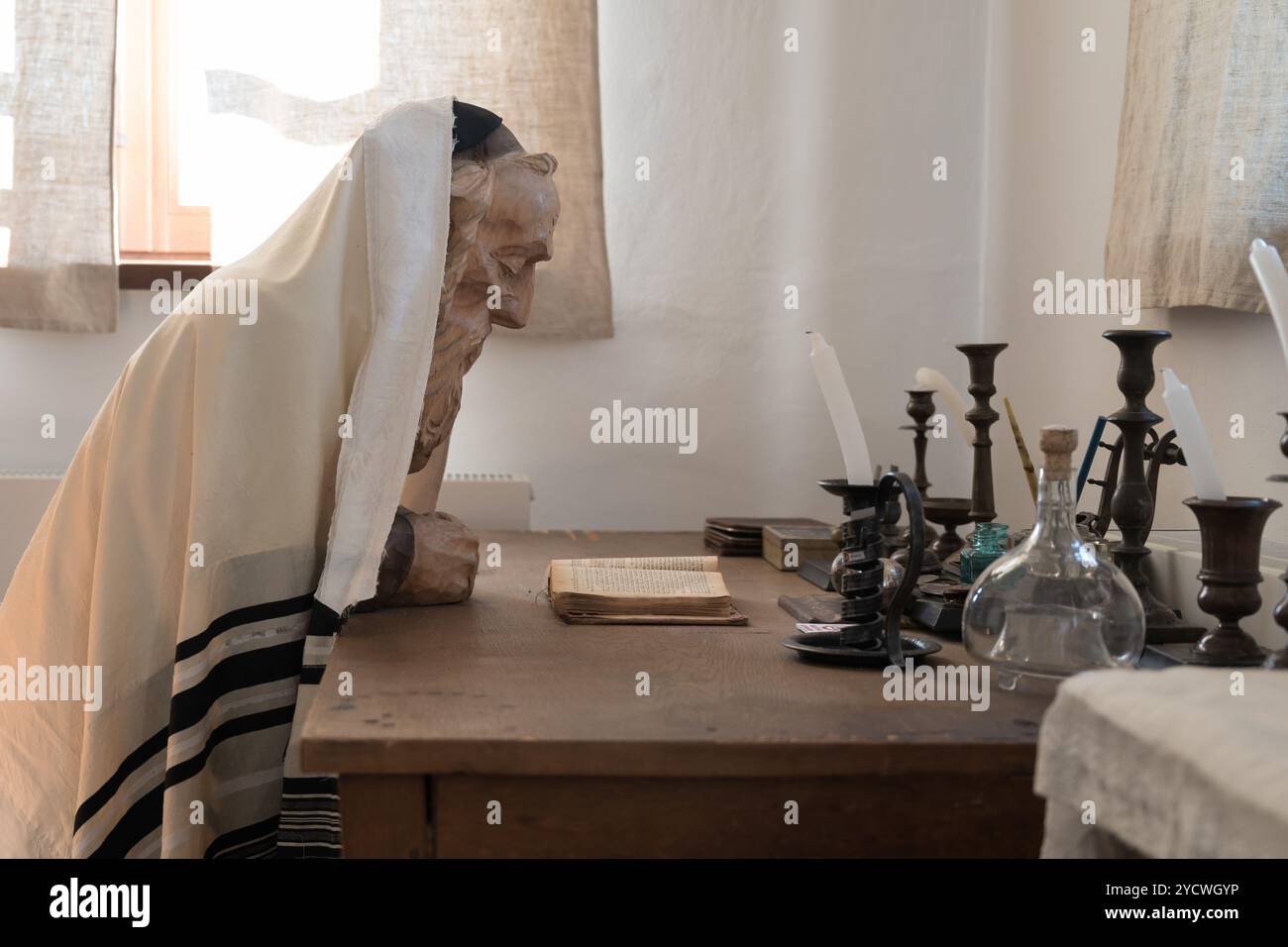 Figura di cera di un vecchio ebreo saggio che indossa un scialle di preghiera o un tallith che studia il testo sacro ebraico Torah a tavola Foto Stock
