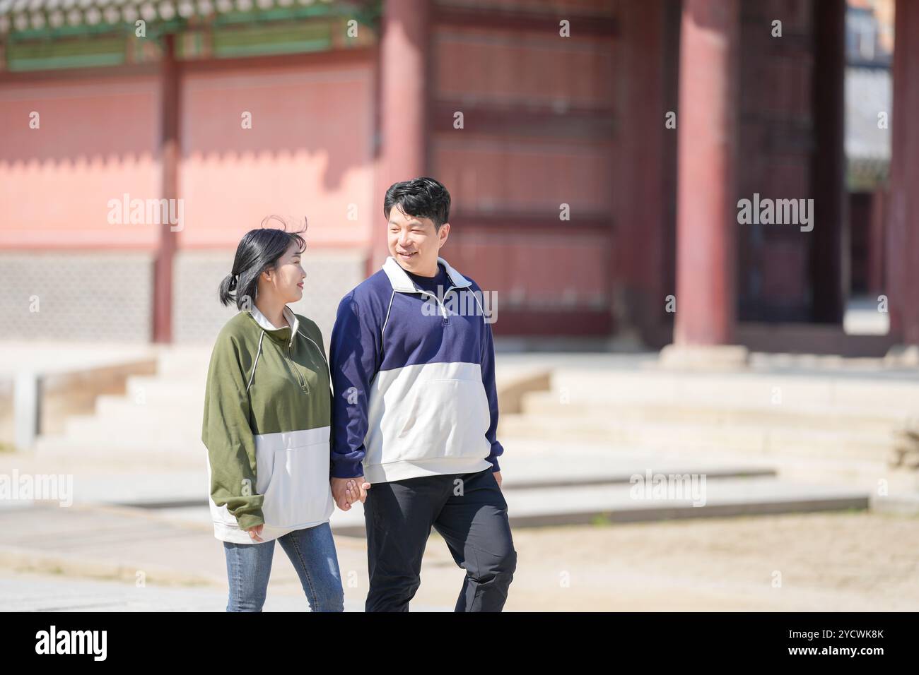 Una coppia coreana sportiva, un uomo di 30 anni e una donna di 20 anni, che indossa tute, trascorrono il loro tempo insieme felicemente in un edificio storico di se Foto Stock