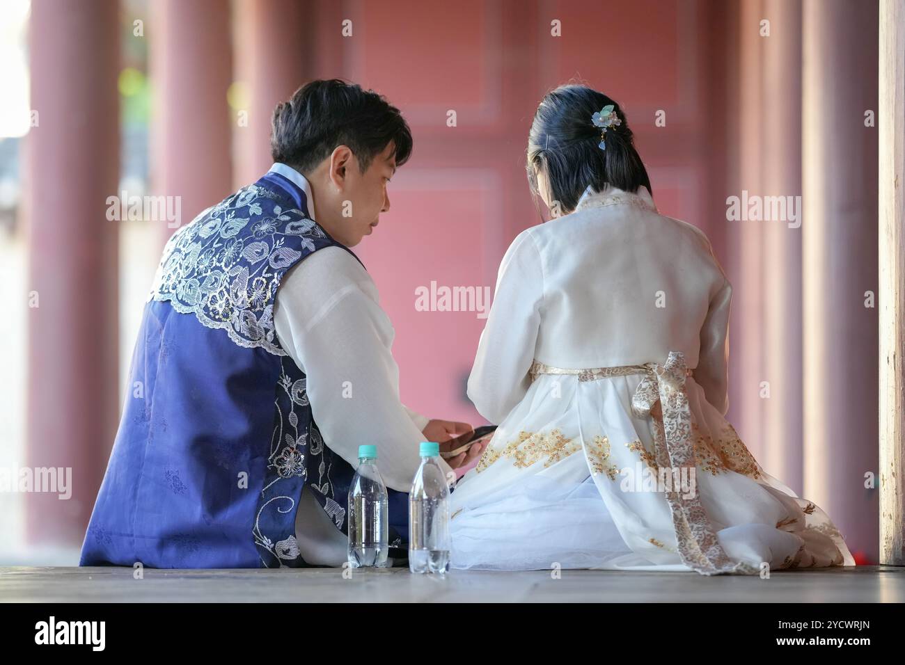 Una coppia coreana, un uomo di 30 anni e una donna di 20 anni, indossa felicemente Hanbok e siede in un edificio storico a Seoul, Corea del Sud. Foto Stock