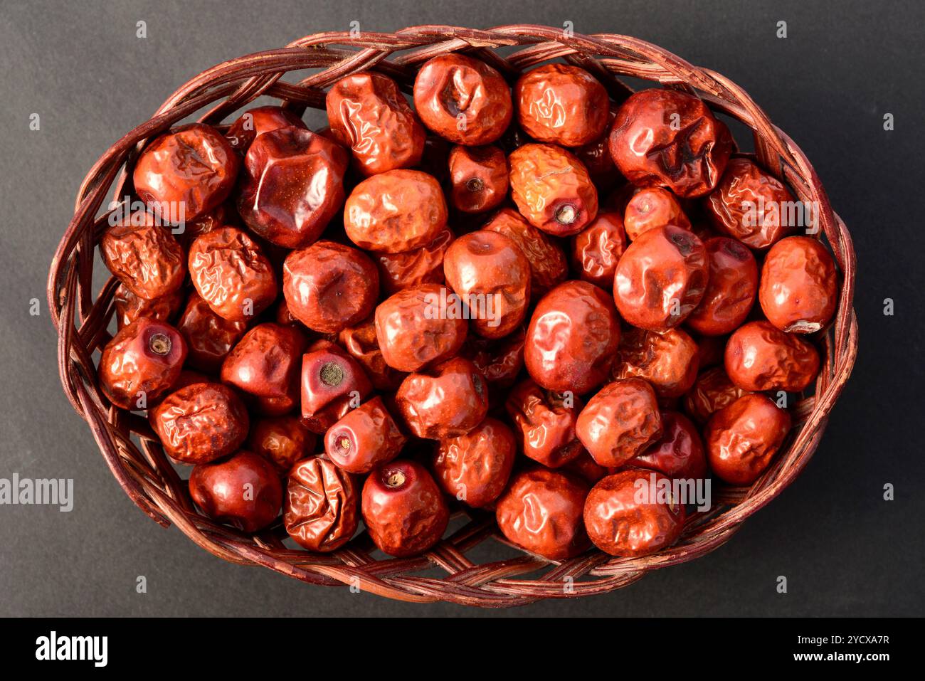 Jujube secca Ziziphus juba frutta in cesto di legno vista dall'alto su sfondo nero Foto Stock