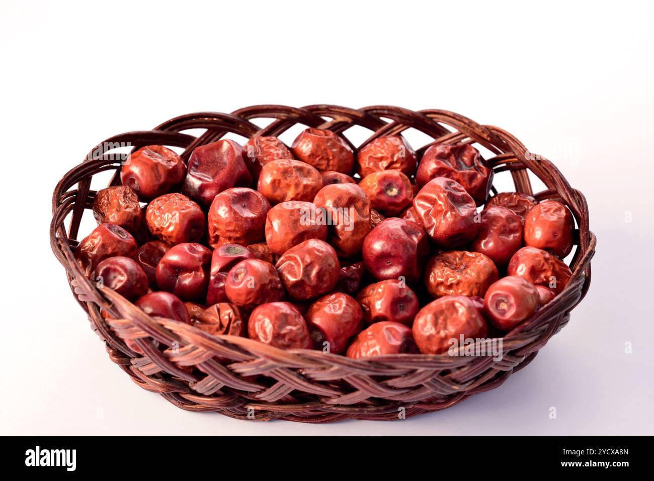 Jujube secca Ziziphus juba frutta in un piccolo cestino di legno vista dall'alto su sfondo bianco Foto Stock