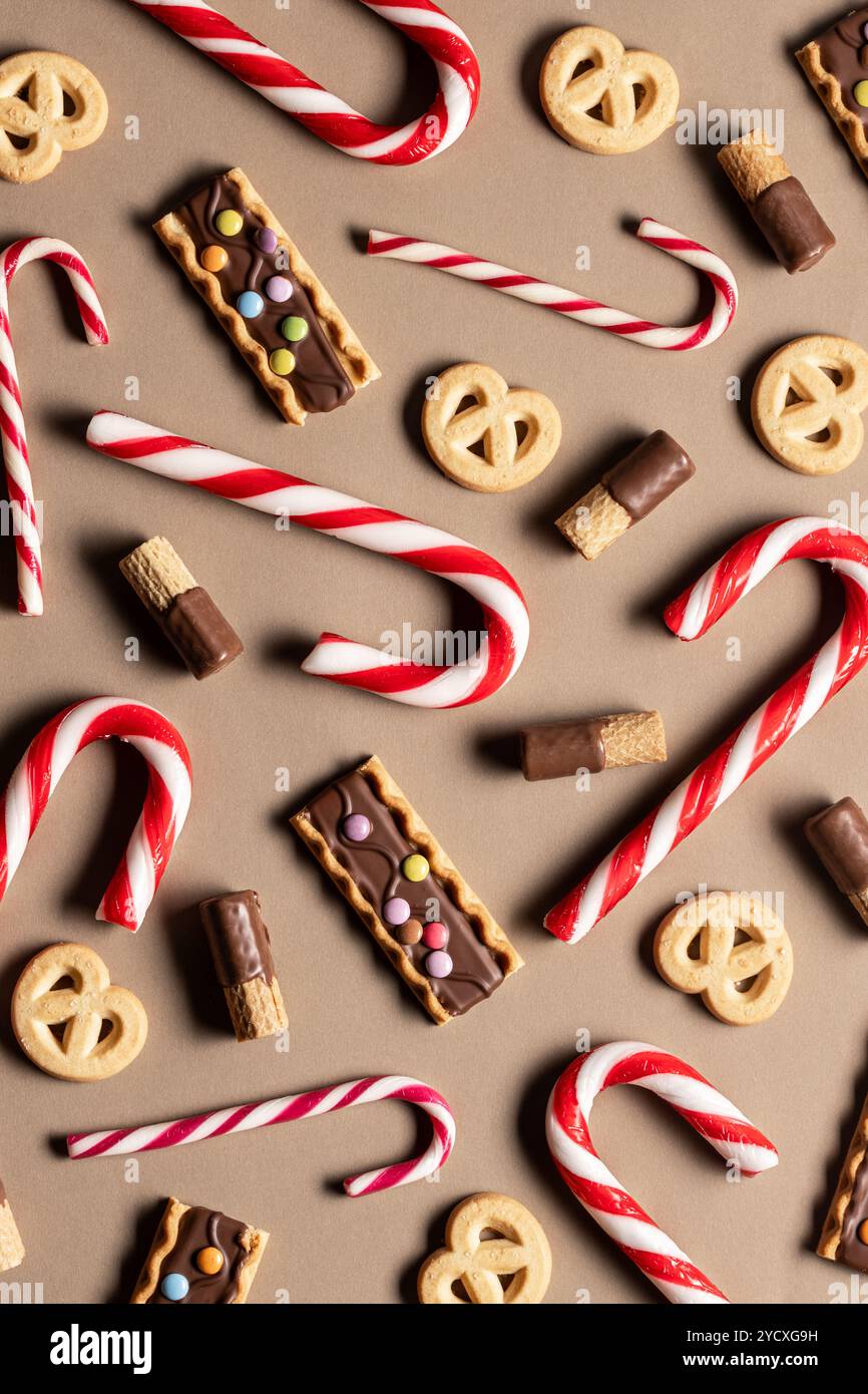 Vista dall'alto di una composizione di dolci natalizi, tra cui canne di caramelle rosse e bianche, biscotti ricoperti di cioccolato con guarnizioni colorate e butte Foto Stock