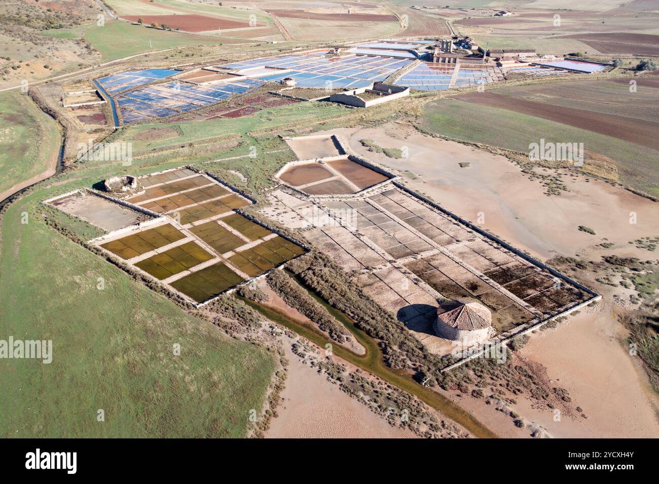 Un vivace drone aereo che cattura le antiche distese saline di Imon, Guadalajara, mostrando le texture e i colori unici formati da plastica, acqua e S. Foto Stock