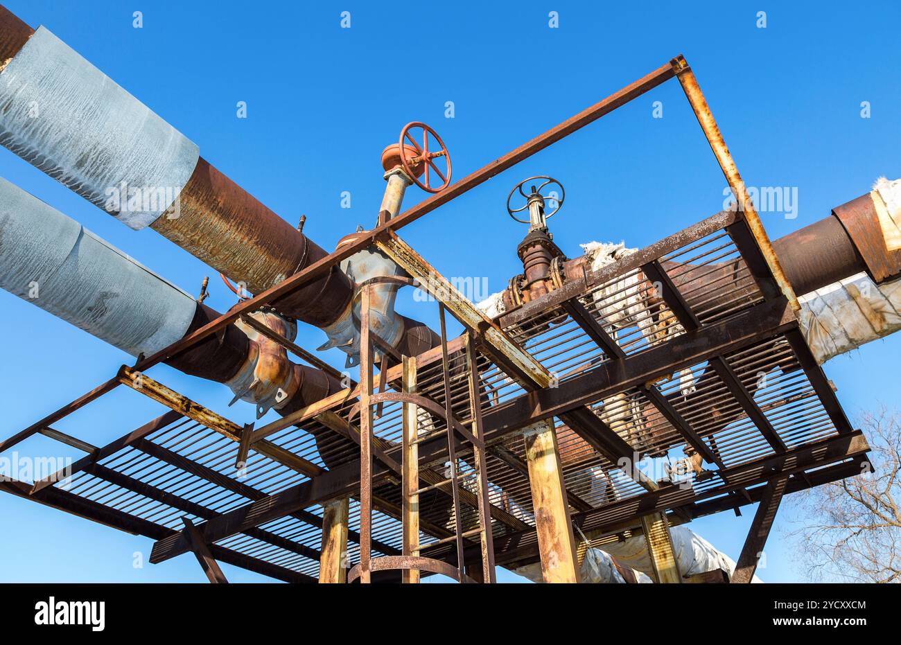 Vecchio arrugginito pipeline con valvole contro il cielo blu sullo sfondo Foto Stock