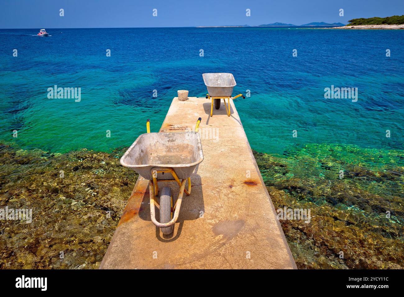 Carriola sulla piccola isola di dock di attesa per la consegna delle merci Foto Stock