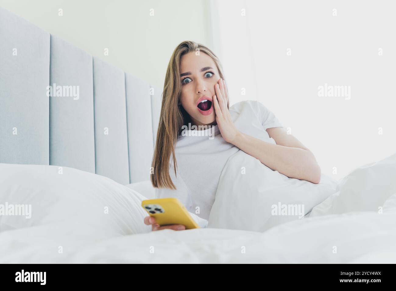 Foto di una signora piuttosto impressionata vestita da sonnambuliere, letto rilassante che digita un moderno gadget all'interno della casa Foto Stock