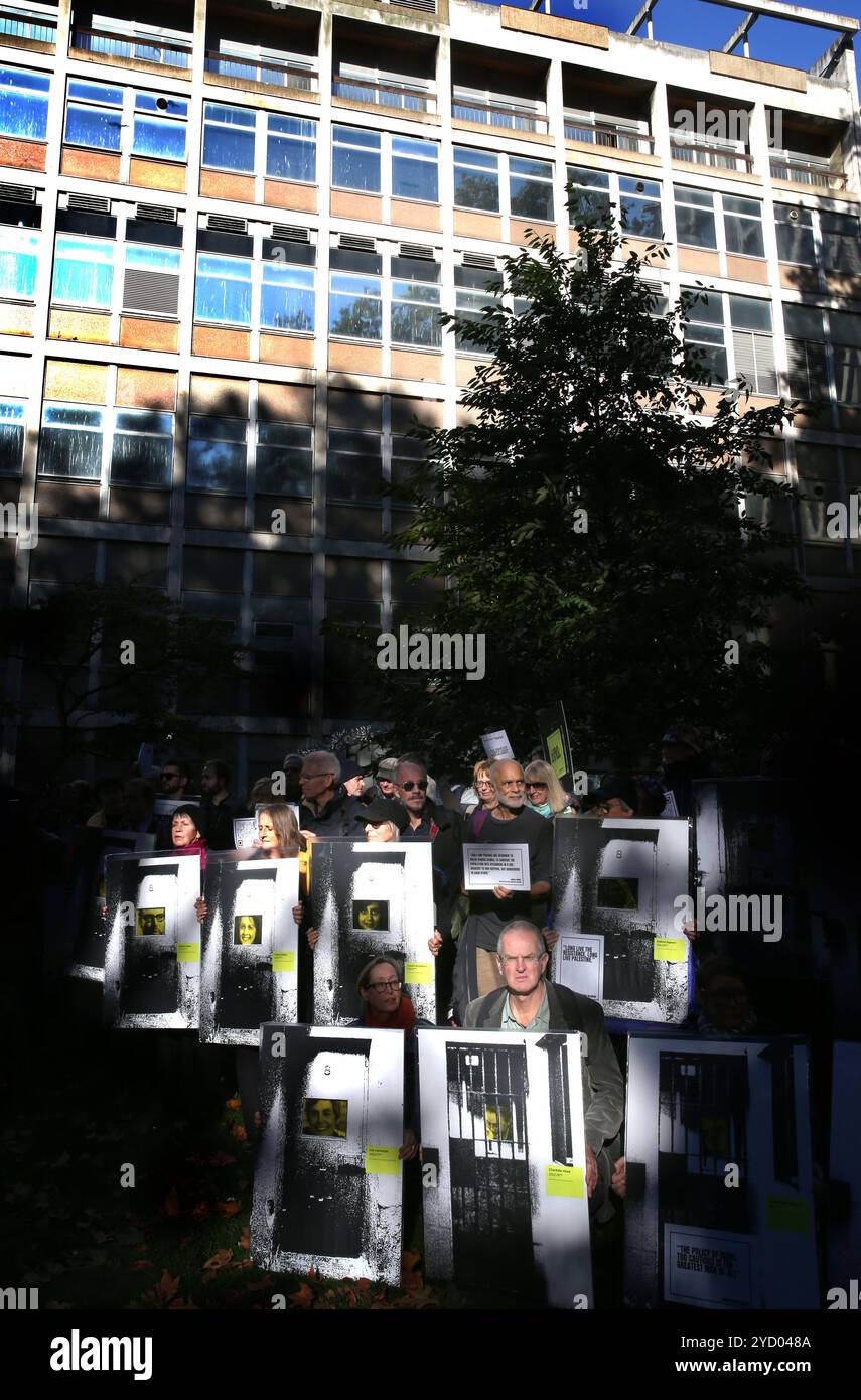 Londra, Inghilterra, Regno Unito. 24 ottobre 2024. Un raggio di luce solare illumina i manifestanti mentre si riuniscono per marciare sul Ministero della giustizia con cartelli e striscioni. I manifestanti hanno segnalato i segni di prigionieri politici imprigionati fuori dal Ministero della giustizia di Londra. I manifestanti si riuniscono fuori dall'ufficio del Procuratore generale in silenzio e tengono segnali a sostegno dei prigionieri politici. Le fotografie del prigioniero appaiono sui cartelli. I manifestanti stanno sottolineando il fatto che, su istruzione dei giudici, molti attivisti incarcerati non sono stati in grado di spiegare pienamente perché hanno intrapreso l'azione che hanno intrapreso Foto Stock