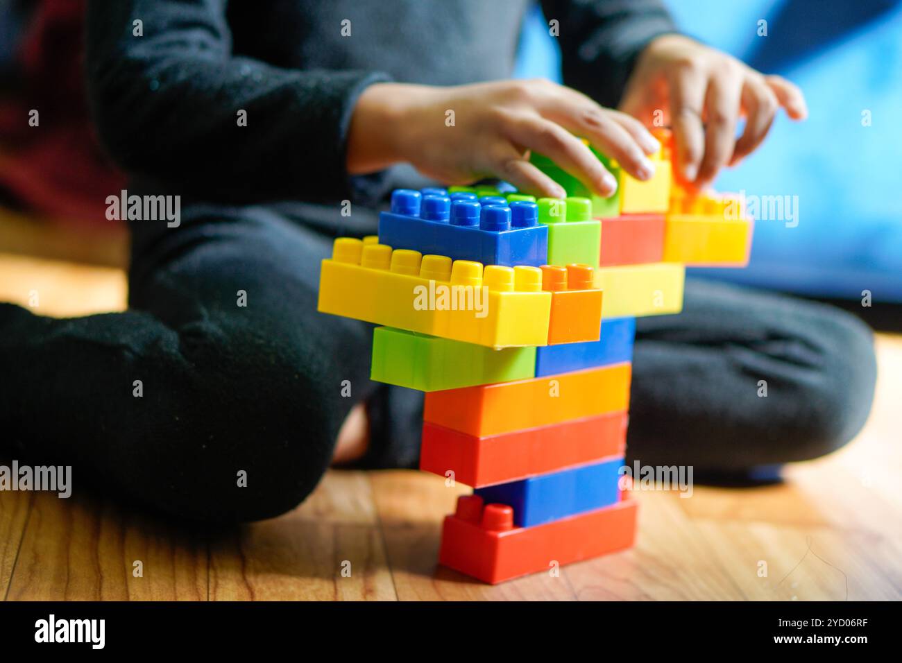 Blocchi di plastica colorati sparsi intorno a un pavimento in legno, che mostrano un momento di creatività e di gioco con colori vivaci Foto Stock