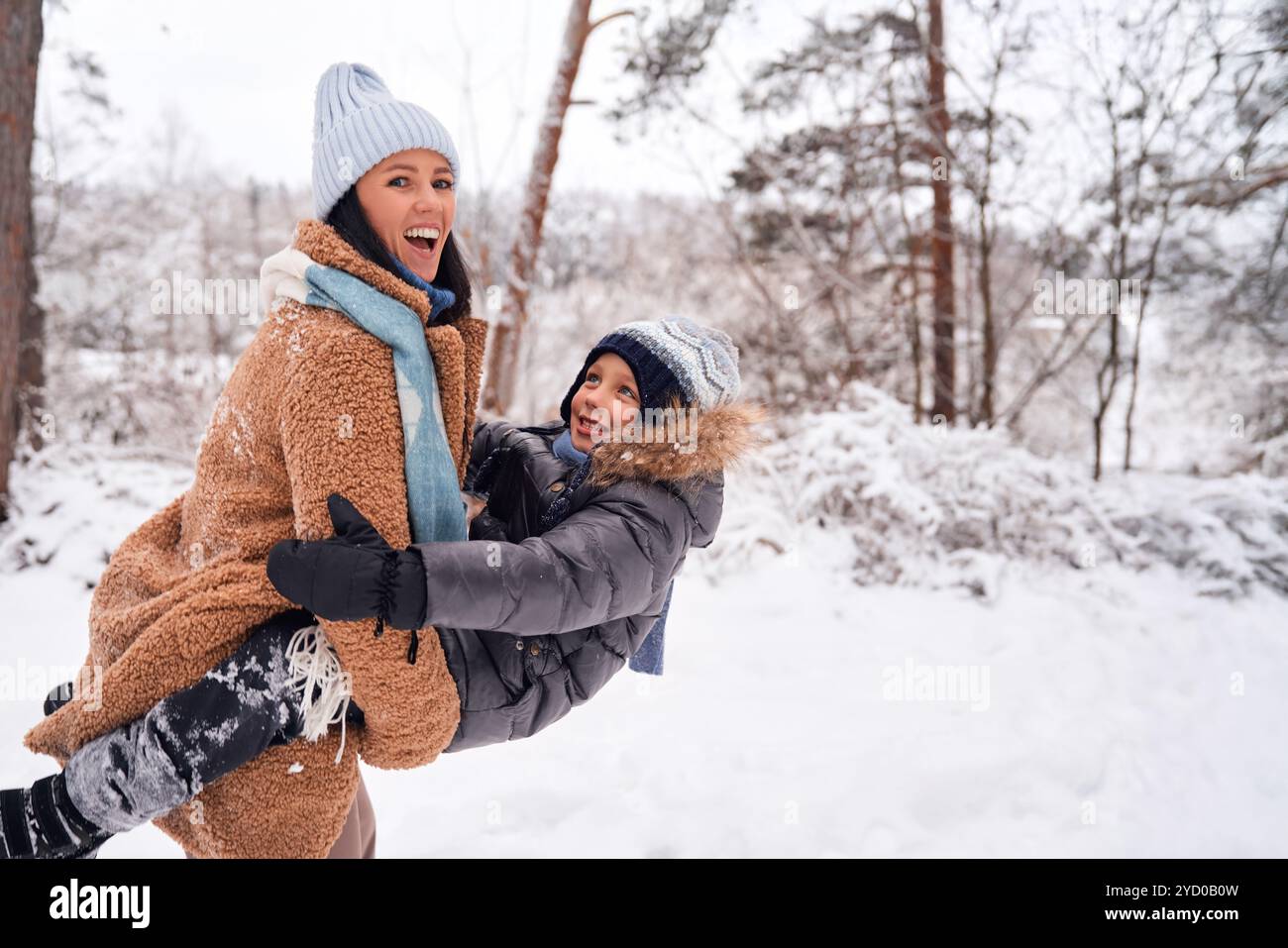 Un momento di gioia tra una madre e un bambino che giocano sulla neve, catturando l'essenza della felicità invernale. Foto Stock