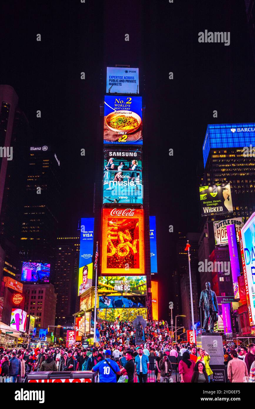 La vivace Times Square di notte, illuminata da iconici cartelloni pubblicitari e folle di turisti. New York. STATI UNITI. Foto Stock