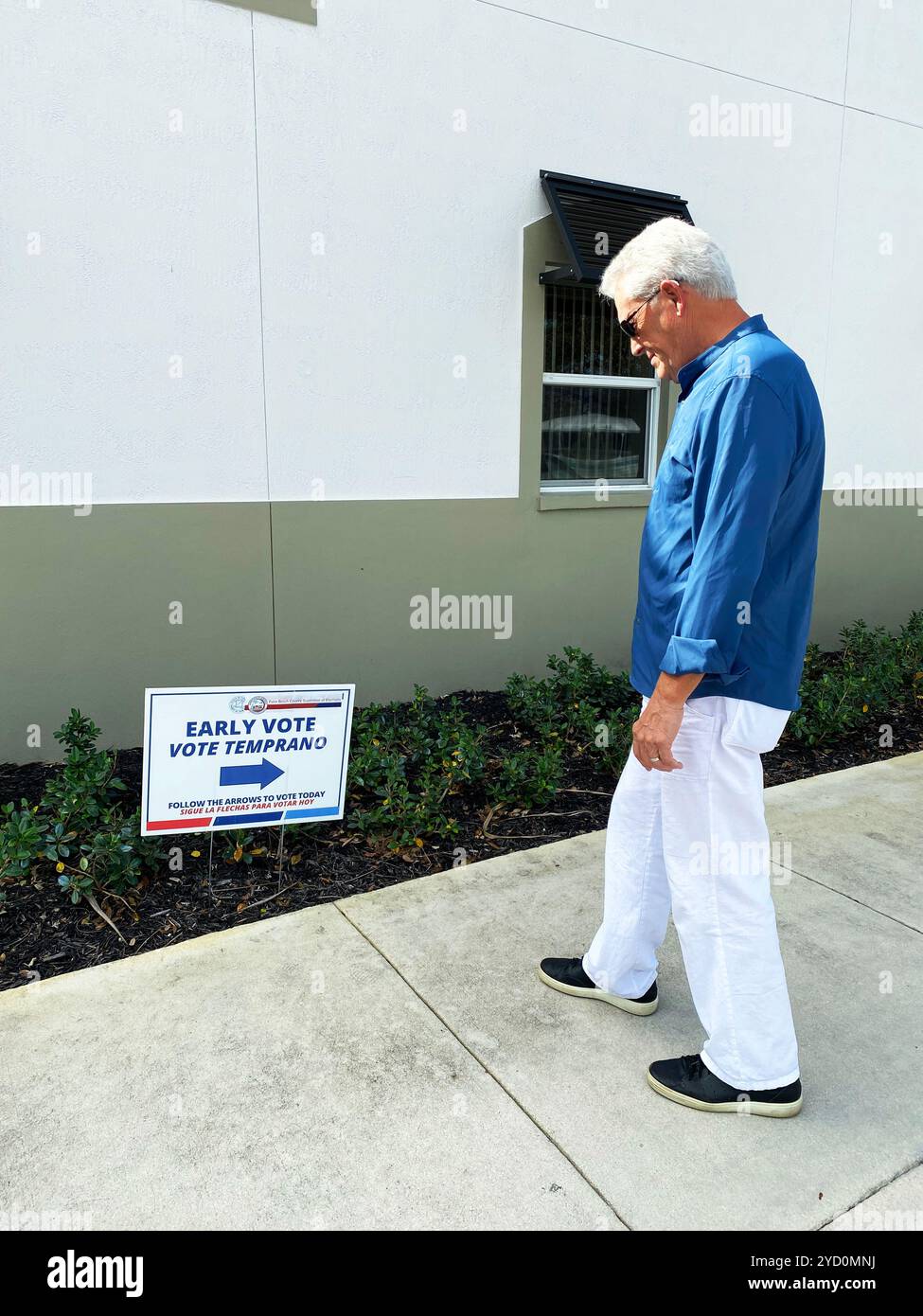 Senior man outdoor che legge un cartello per la votazione anticipata in Florida, 22 ottobre 2024, Palm Beach County. - Immagine stock catturata con smartphone