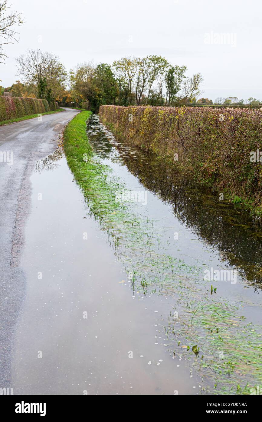 Un canale di drenaggio traboccante dopo forti piogge in una corsia vicino al villaggio di Clanfield, Oxfordshire, Inghilterra Regno Unito Foto Stock