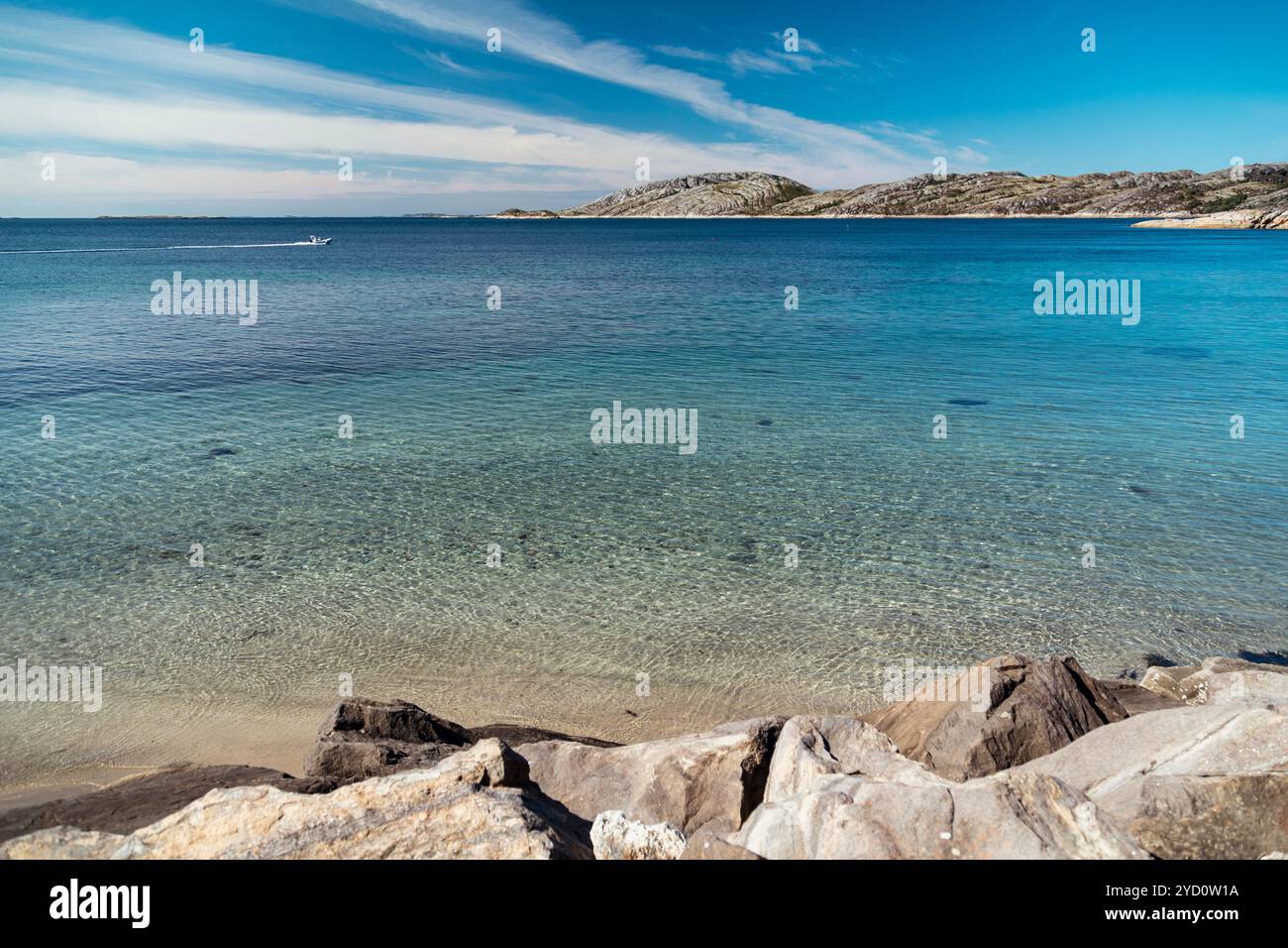 Una serata tranquilla si svolge in una spiaggia di Bodo, nella contea di Nordland, dove le acque calme riflettono il cielo, e le dolci onde si infrangono contro la costa rocciosa, invit Foto Stock