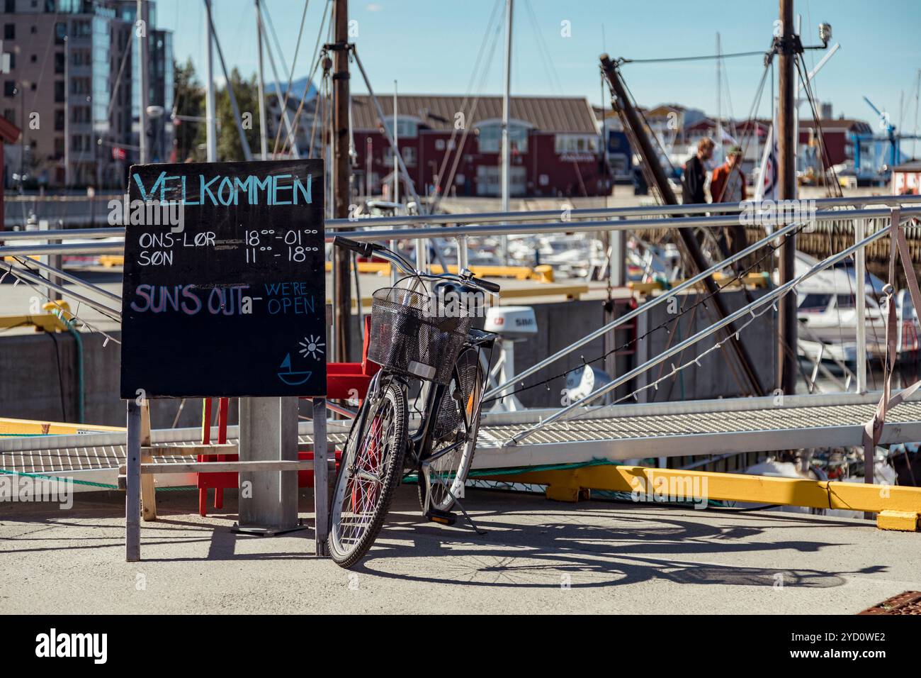 Al porto di Bodo, Nordland, una bicicletta ibrida si appoggia su un cartello di benvenuto, invitando i visitatori a godersi il bellissimo paesaggio e le attività all'aperto Foto Stock