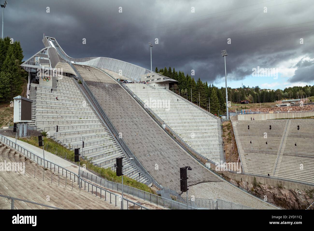 L'impressionante pista di salto con gli sci di Holmenkollen presenta un suggestivo design anfiteatro circondato da alberi, con nuvole che incombono drammaticamente sopra il c Foto Stock