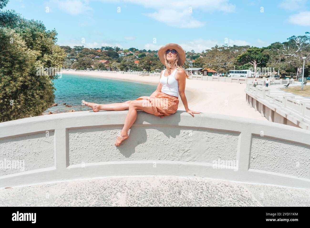 Donna che si rilassa sul ponte ad arco godendosi il sole estivo Foto Stock