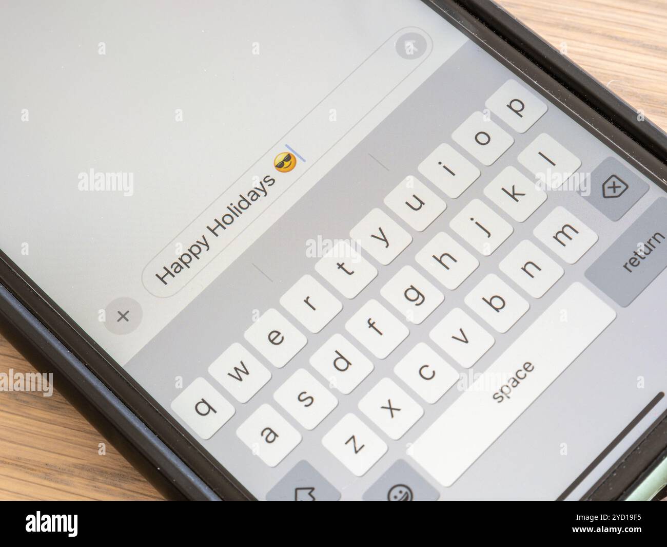 Vista ravvicinata dello schermo di un telefono cellulare che mostra un messaggio di testo in una conversazione con emoji che dice: Buone feste Foto Stock