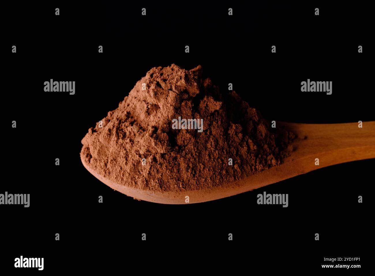 Colpo ad angolo alto di cucchiaio di legno con cacao in polvere su sfondo nero Foto Stock