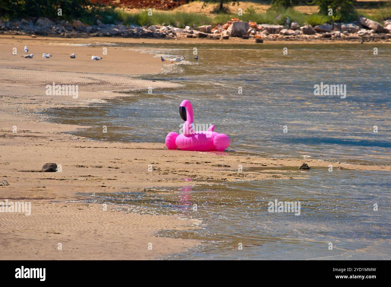 Anello di nuoto del fenicottero rosa abbandonato sulla spiaggia di sabbia Foto Stock