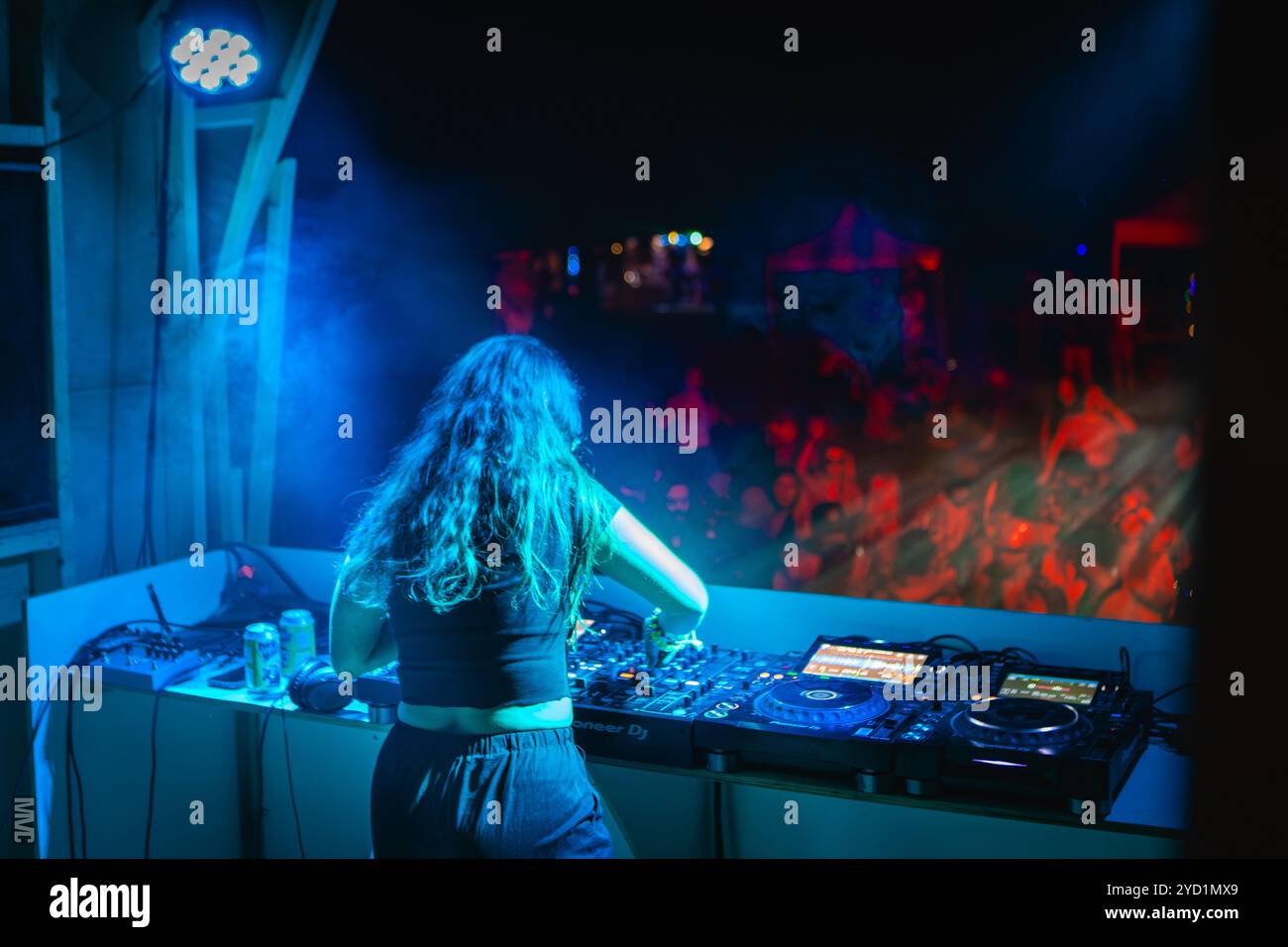 DJ sul palco che suona musica per la folla di sera al rave festival Foto Stock