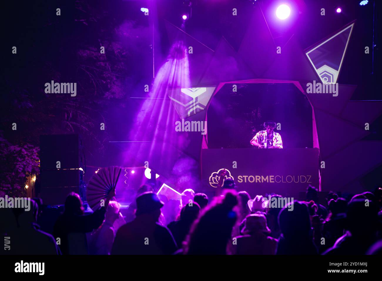 DJ sul palco che suona musica per la folla di sera al rave festival Foto Stock