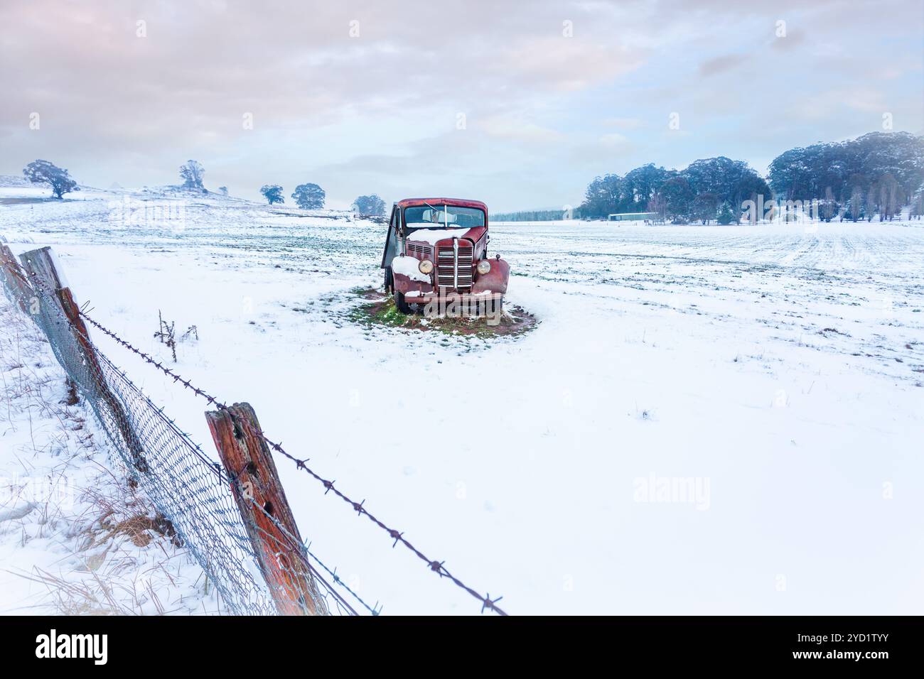 Rusty vecchia macchina si trova in un campo rurale coperto di neve Foto Stock